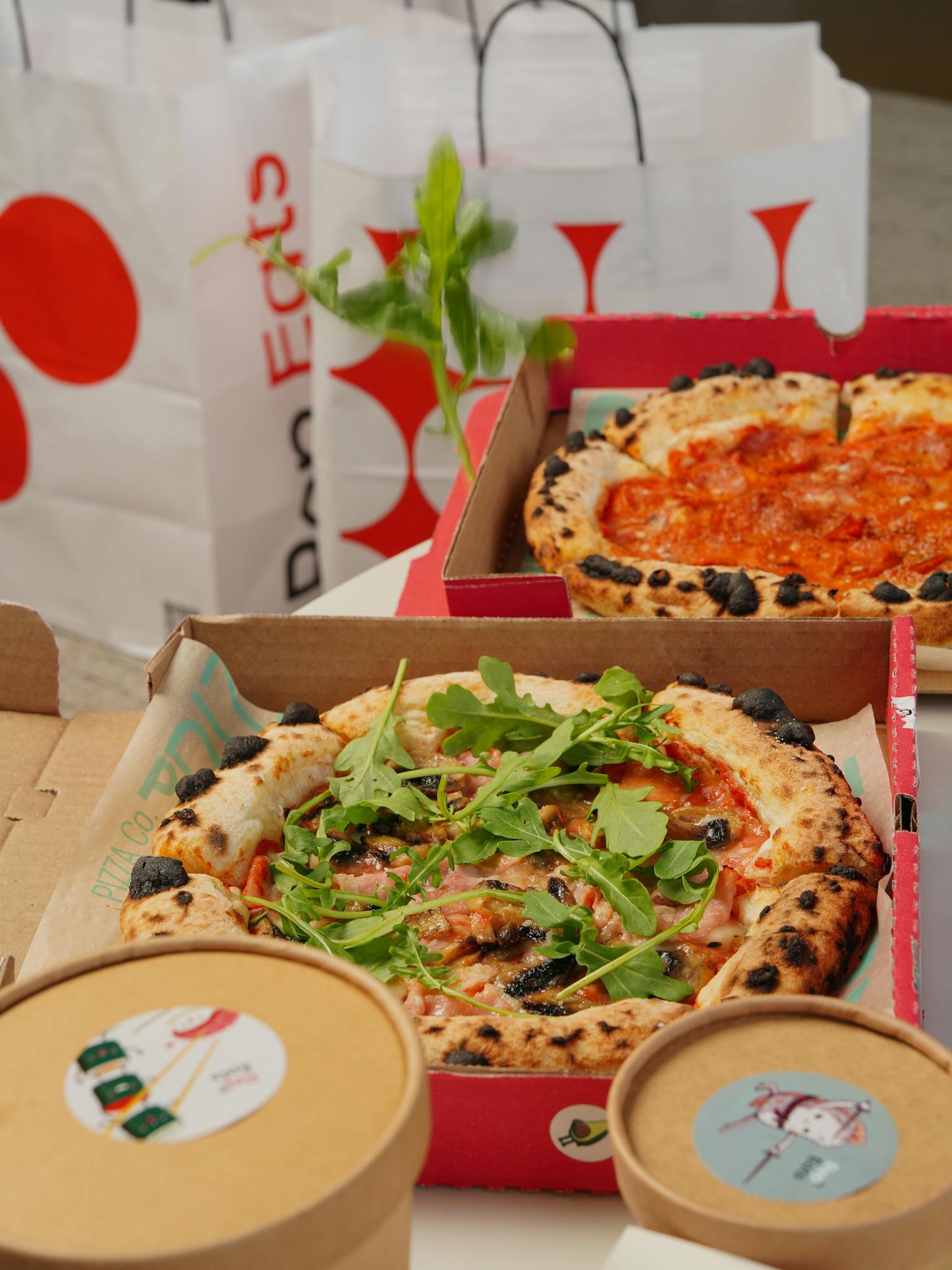 Assorted pizzas in takeout boxes with bags in the background, showcasing fresh toppings.