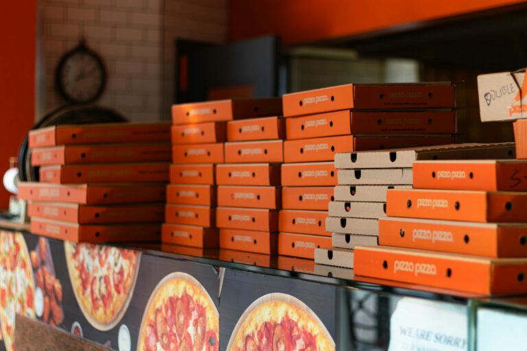 Orange pizza boxes stacked in a Toronto pizzeria, showcasing vibrant packaging.